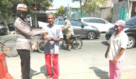 Polwan sedang membagikan nasi bungkus pada kaum duafa dikawasan Jombang Kota. 