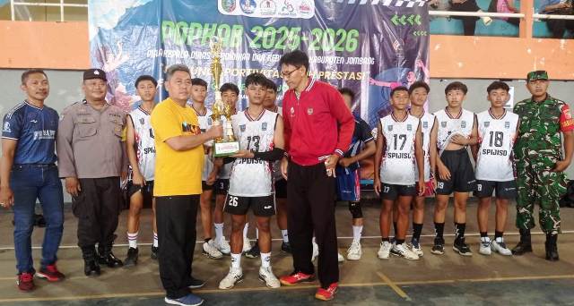 Ketua MKKS SMP Negeri di Jombang Yony Tri Joko Kurnianto (kaos kuning) menyerahkan Piala kepada tim putra SMP Negeri 1 Ploso yang telah membuktikan kemampuannya menjadi juara 1, cabor bola voli di GOR Merdeka, Minggu (9/11/2025). 