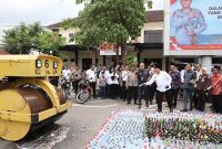 Tampak Bupati Jombang, Warsubi, S.H., M.Si., sedang melempar botol berisi miras ke alat berat untuk dimusnahkan, turut memusnahkan diantaranya, Ketua DPRD Jombang, jajaran Forkopimda Jombang, para tokoh agama termasuk KH. Nur Hadi (Mbah Bolong), juga tokoh Masyarakat, Kamis (18/2/2026).

