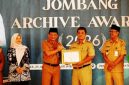 Bupati Jombang yang diwakili oleh Sekretaris Daerah Kabupaten Jombang Agus Purnomo S.H., M.Si menyerahkan penghargaan kepada Thonsom Pranggono A.P., M.E., Kepala Dinas Perpustakaan dan Kearsipan (Disperpusip) sukses menempati urutan pertama dengan raihan nilai tertinggi sebesar 98,10 (meningkat dari 89,65 di tahun 2025). 