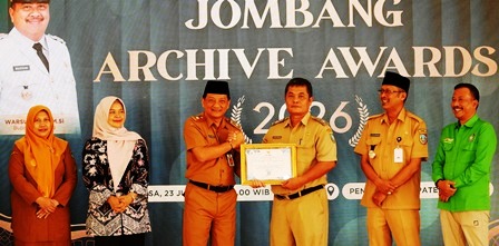 Bupati Jombang yang diwakili oleh Sekretaris Daerah Kabupaten Jombang Agus Purnomo S.H., M.Si menyerahkan penghargaan kepada Thonsom Pranggono A.P., M.E., Kepala Dinas Perpustakaan dan Kearsipan (Disperpusip) sukses menempati urutan pertama dengan raihan nilai tertinggi sebesar 98,10 (meningkat dari 89,65 di tahun 2025). 
