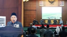 Wakil Bupati Jombang Salmanudin, S.Ag., M.Pd (kiri) menyampaikan jawaban Bupati terhadap Pemandangan Umum (PU) Fraksi-Fraksi DPRD terkait Rancangan Peraturan Daerah (Raperda) tentang Penyelenggaraan Jasa Konstruksi. Rapat Paripurna dihadiri langsung Bupati Jombang Warsubi, S.H., M.Si,  jajaran Forkopimda, Sekretaris Daerah Kabupaten (Sekdakab), serta para Kepala Organisasi Perangkat Daerah (OPD) di lingkup Pemkab Jombang, Senin (8/6/2026). 